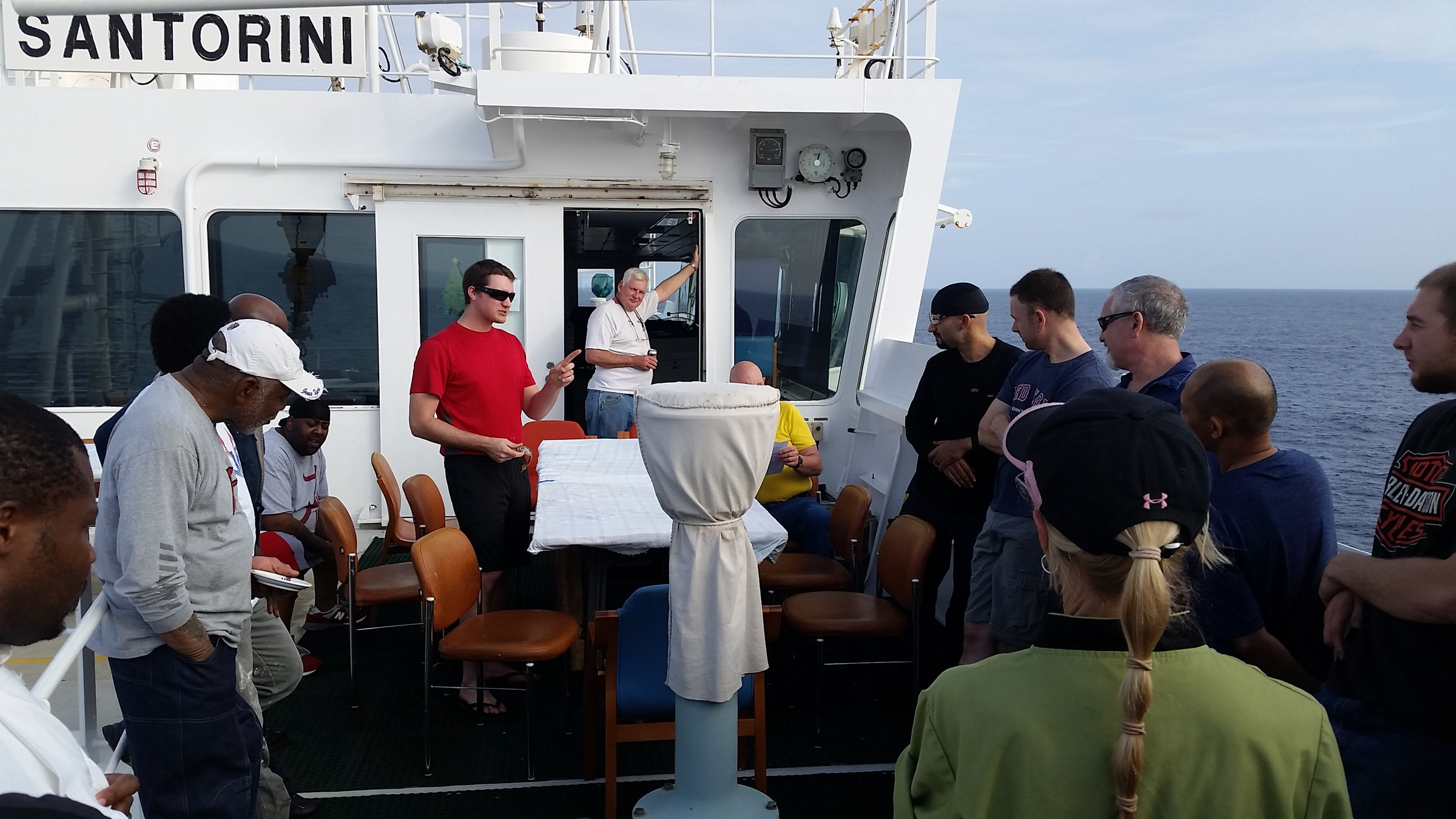 Alex Hays on the bridge of the working ship Santorini, leading a crew briefing.